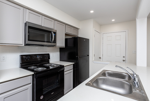 a kitchen with white cabinets and black appliances and a sink